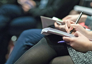 Zuhörerin eines Vortrags mit Notizbuch